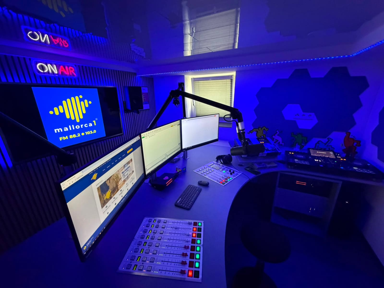 Blick über das Sendepult im blau beleuchteten Studio, im Hintergrund die ON-AIR-Leuchte